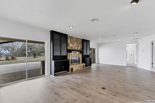 unfurnished living room with a fireplace, wood finished floors, and visible vents