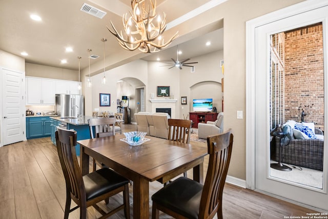 dining area with visible vents, arched walkways, light wood-type flooring, a fireplace, and recessed lighting