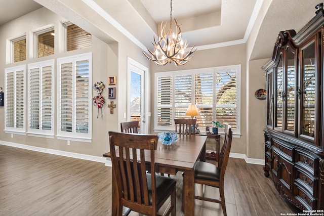 dining space with a notable chandelier, dark wood-type flooring, a raised ceiling, and baseboards