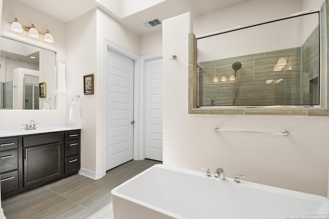 full bathroom with a stall shower, visible vents, a freestanding bath, and vanity