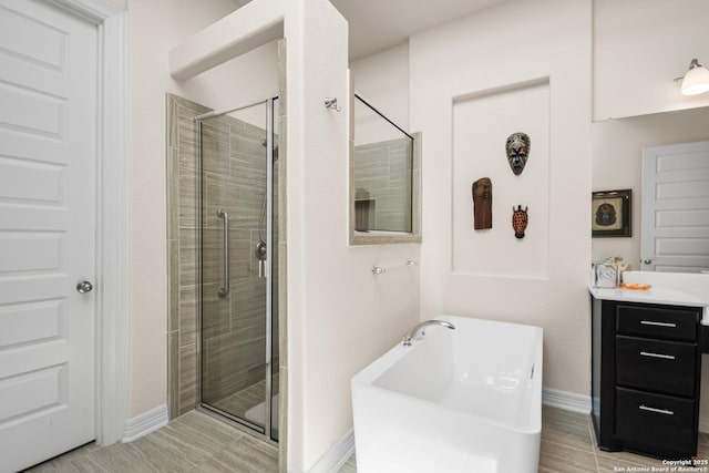 full bathroom with a freestanding bath, wood tiled floor, a shower stall, vanity, and baseboards