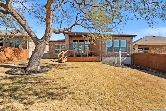 rear view of property with a yard, fence, and brick siding