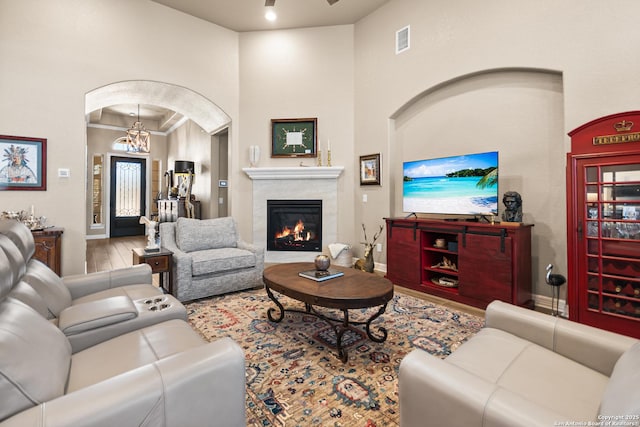 living room with baseboards, visible vents, arched walkways, a premium fireplace, and wood finished floors