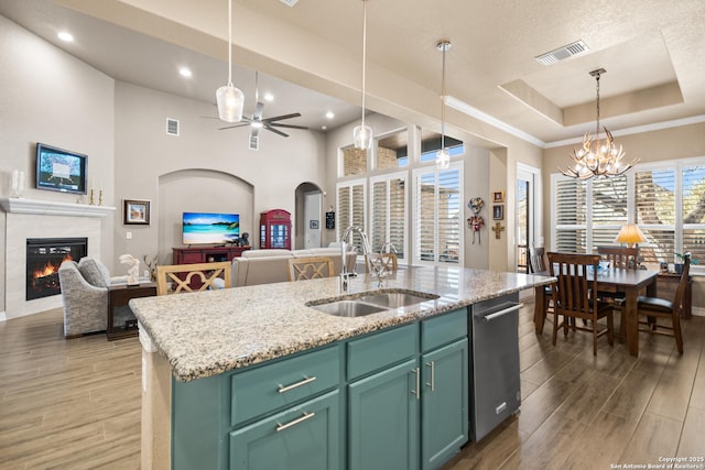 kitchen featuring a tray ceiling, visible vents, wood tiled floor, open floor plan, and a sink