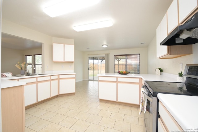 kitchen with light countertops, stainless steel range with electric cooktop, a sink, a peninsula, and under cabinet range hood