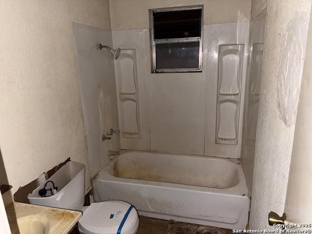 full bathroom featuring toilet, a textured wall, tub / shower combination, and vanity