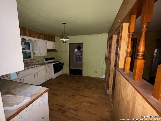 kitchen with white cabinets, dark wood finished floors, under cabinet range hood, pendant lighting, and range with electric stovetop