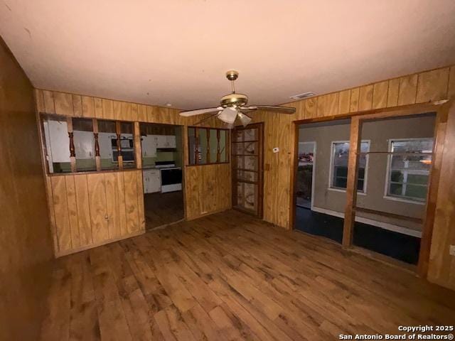 kitchen featuring ceiling fan, wood walls, wood finished floors, visible vents, and white electric range oven