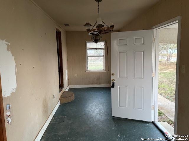 unfurnished dining area featuring baseboards, a chandelier, and concrete flooring