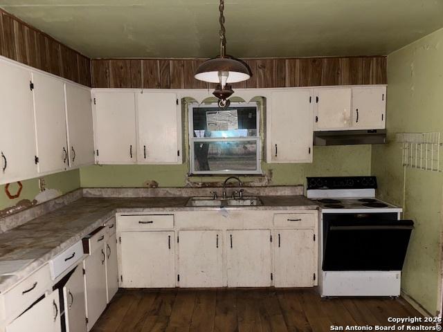 kitchen featuring white electric stove, dark wood-type flooring, under cabinet range hood, white cabinetry, and a sink