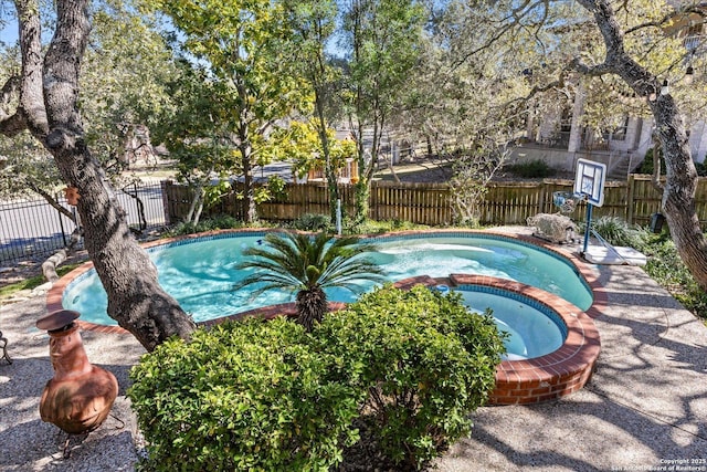 view of swimming pool featuring a pool with connected hot tub and a fenced backyard