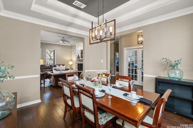 dining room with a raised ceiling, visible vents, a fireplace, and hardwood / wood-style floors