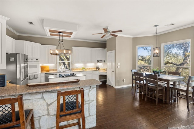 kitchen featuring stainless steel appliances, ornamental molding, dark wood finished floors, and visible vents