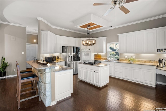 kitchen featuring crown molding, stainless steel appliances, dark wood-type flooring, white cabinetry, and a peninsula