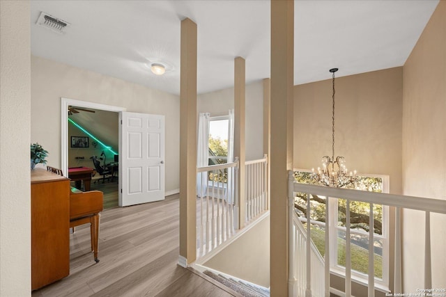 hallway featuring an upstairs landing, wood finished floors, visible vents, and an inviting chandelier