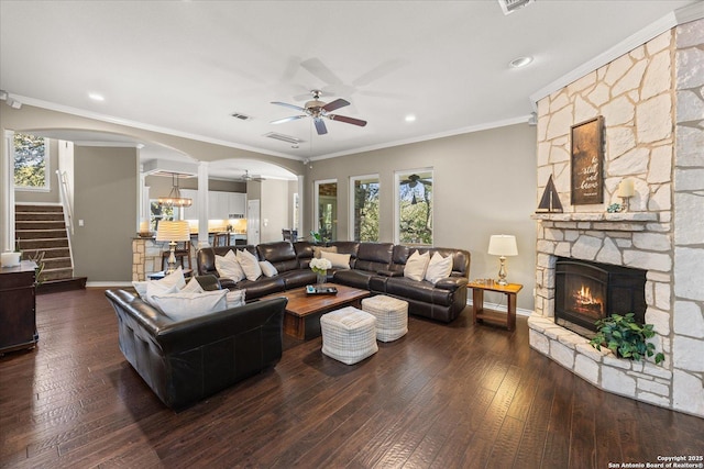 living room featuring arched walkways, a fireplace, wood-type flooring, stairway, and ornamental molding