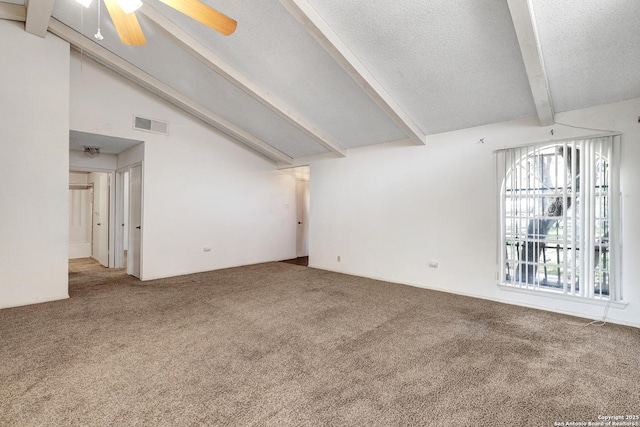 carpeted spare room with vaulted ceiling with beams, ceiling fan, visible vents, and a textured ceiling