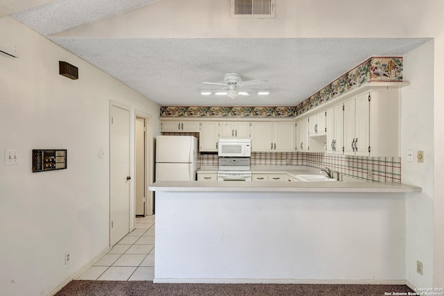 kitchen with white appliances, visible vents, a peninsula, light countertops, and a sink