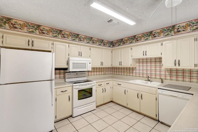 kitchen with light countertops, visible vents, a sink, a textured ceiling, and white appliances