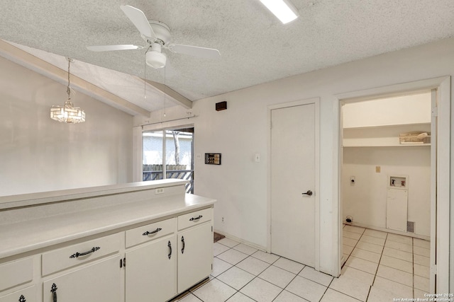 kitchen featuring light tile patterned floors, light countertops, white cabinetry, vaulted ceiling, and a textured ceiling