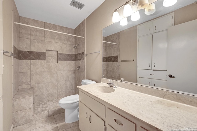 bathroom featuring visible vents, toilet, a tile shower, vanity, and tile patterned floors