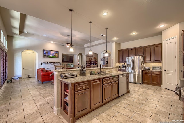 kitchen with arched walkways, stainless steel appliances, open floor plan, and a sink