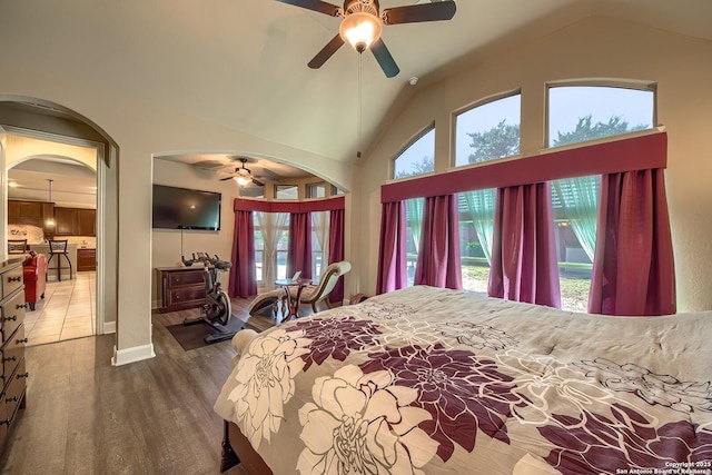 bedroom with high vaulted ceiling, a ceiling fan, arched walkways, and wood finished floors