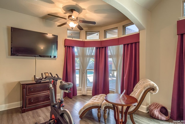 sitting room with ceiling fan, baseboards, arched walkways, and wood finished floors