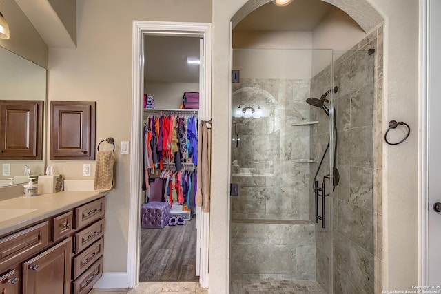 bathroom featuring a walk in closet, a shower stall, and vanity