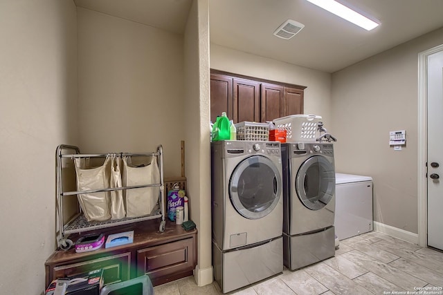 laundry room featuring cabinet space, baseboards, visible vents, and washing machine and clothes dryer