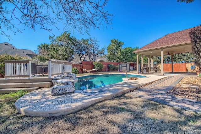 view of pool featuring a patio, a fenced backyard, an outdoor structure, a wooden deck, and a fenced in pool