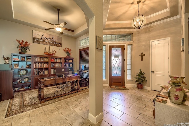 entrance foyer featuring ornamental molding, a raised ceiling, and baseboards