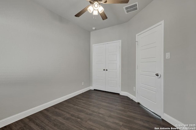 unfurnished bedroom with a closet, dark wood-style flooring, visible vents, and baseboards