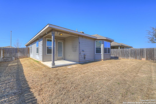 back of house featuring a patio area, a fenced backyard, and a yard