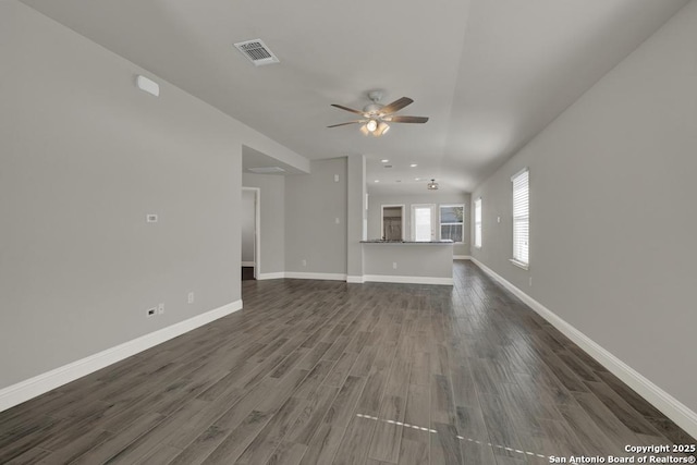 unfurnished living room featuring a ceiling fan, dark wood-style flooring, visible vents, and baseboards