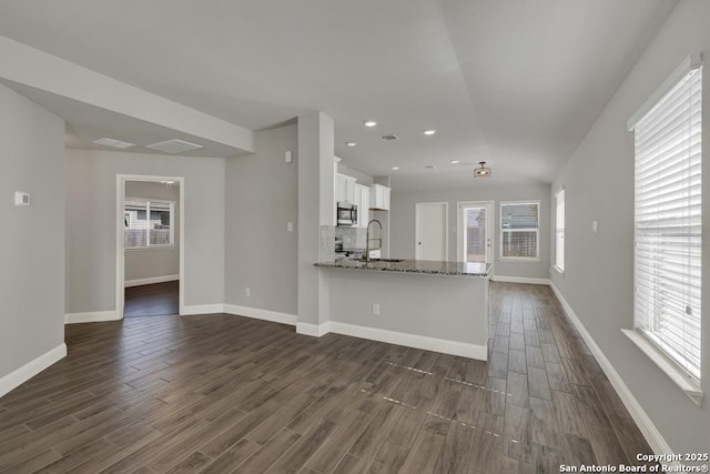 kitchen featuring dark wood-style flooring, stainless steel microwave, light stone countertops, and white cabinets