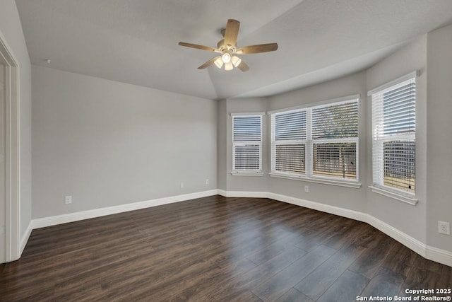 spare room featuring dark wood-style floors, baseboards, vaulted ceiling, and a ceiling fan