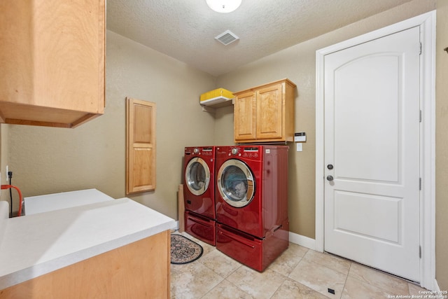 washroom with light tile patterned floors, a textured ceiling, visible vents, cabinet space, and washing machine and clothes dryer