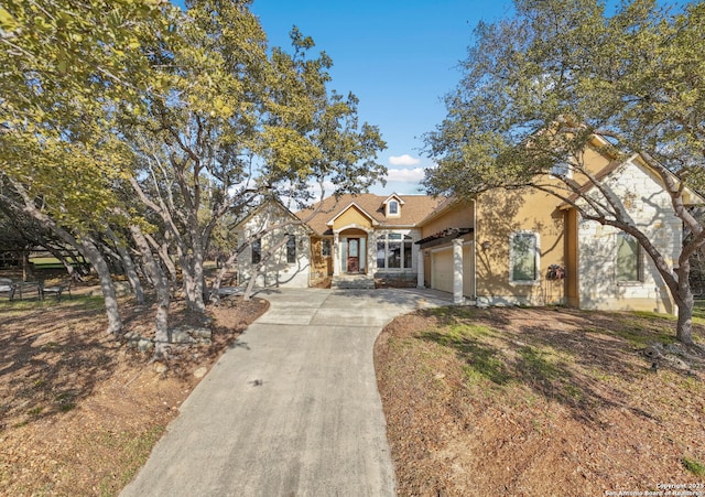 view of front facade featuring an attached garage, driveway, and stucco siding