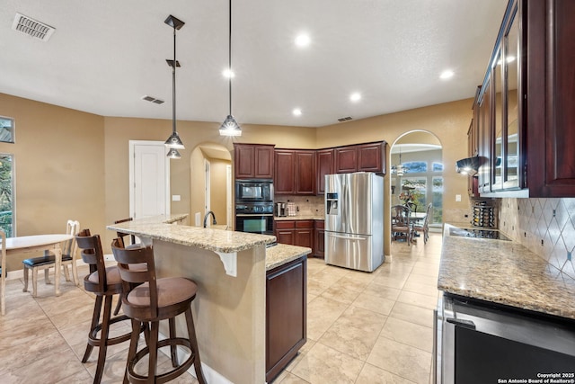 kitchen featuring arched walkways, black appliances, visible vents, and decorative backsplash