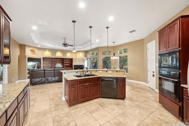 kitchen with visible vents, a lit fireplace, a tray ceiling, black appliances, and a sink