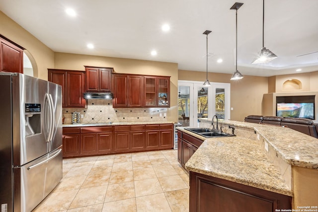 kitchen featuring decorative light fixtures, backsplash, a sink, under cabinet range hood, and stainless steel fridge with ice dispenser