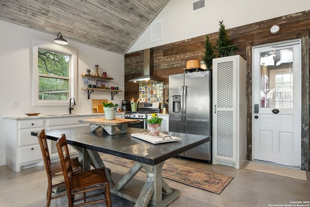 kitchen featuring white cabinetry, visible vents, appliances with stainless steel finishes, wall chimney range hood, and finished concrete floors