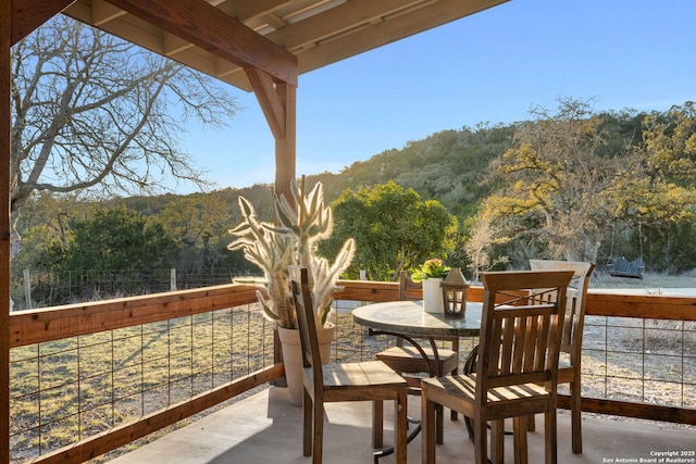 balcony featuring outdoor dining area and a forest view