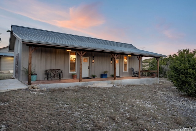 rear view of property with metal roof, a porch, and board and batten siding