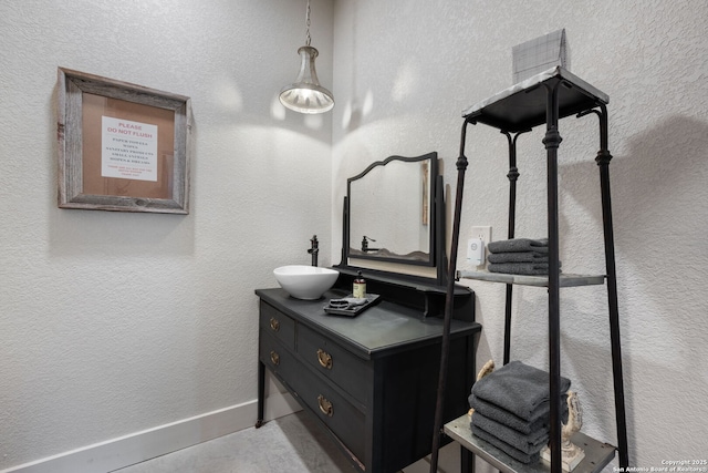 bathroom with a textured wall, vanity, and baseboards