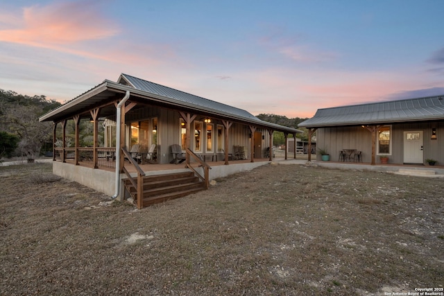 back of property at dusk with a porch, metal roof, and board and batten siding