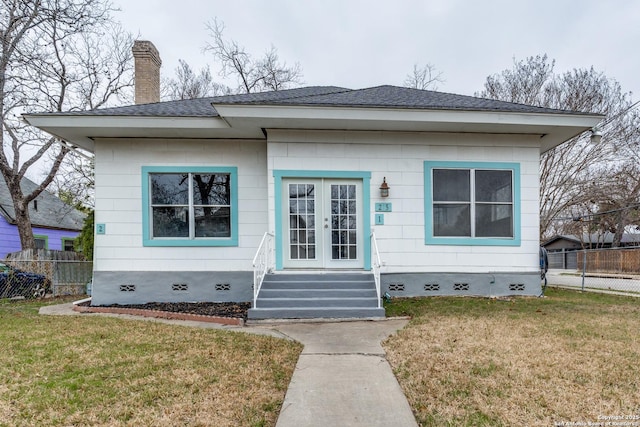 bungalow-style home with a shingled roof, crawl space, fence, french doors, and a front yard