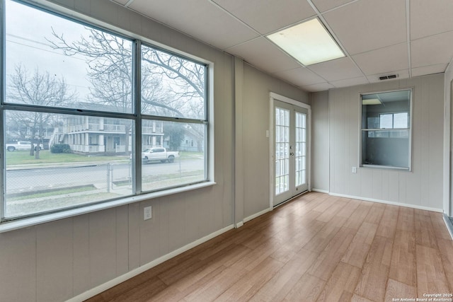 unfurnished room featuring a drop ceiling, visible vents, baseboards, french doors, and light wood-type flooring