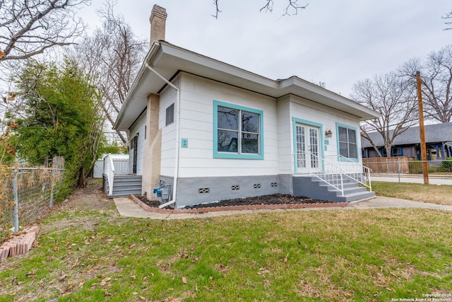 view of front of home featuring fence, french doors, crawl space, a front lawn, and a chimney